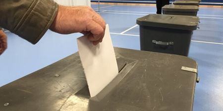 En hånd lægger en stemmeseddel i stemmeurnen. Foto: Frederikssund Kommune.